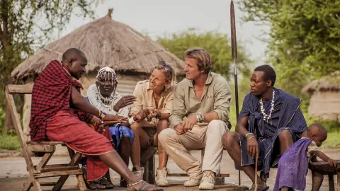 Travellers sitting and talking with a Maasai family outside their homestead