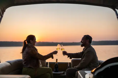 A couple raising a glass at a private sundowner beside the water