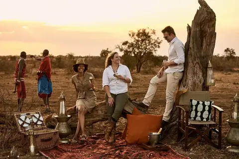 Guests and Maasai hosts gathered for a bush sundowner at dusk