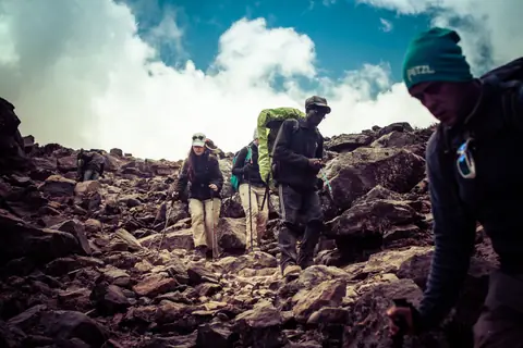 A group picking its way up a boulder field in the mist