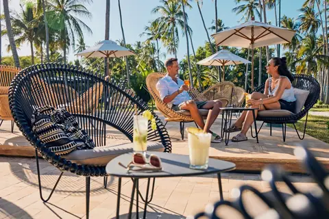 Guests relaxing with drinks under palms at a Zanzibar beach club
