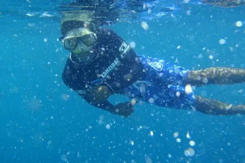 A snorkeller swimming through clear blue water