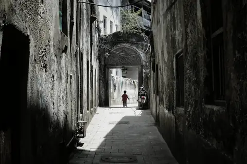 A narrow Stone Town lane between tall coral-rag buildings