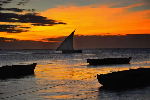 A dhow under sail against an orange Zanzibar sunset