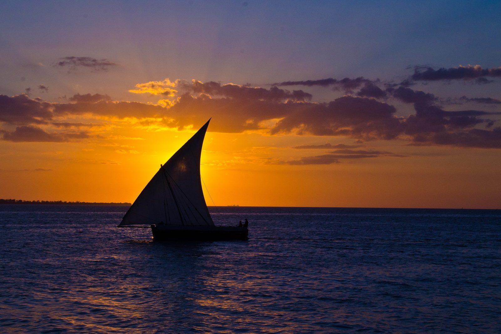 The silhouette of a dhow's sail as the sun drops into the Indian Ocean