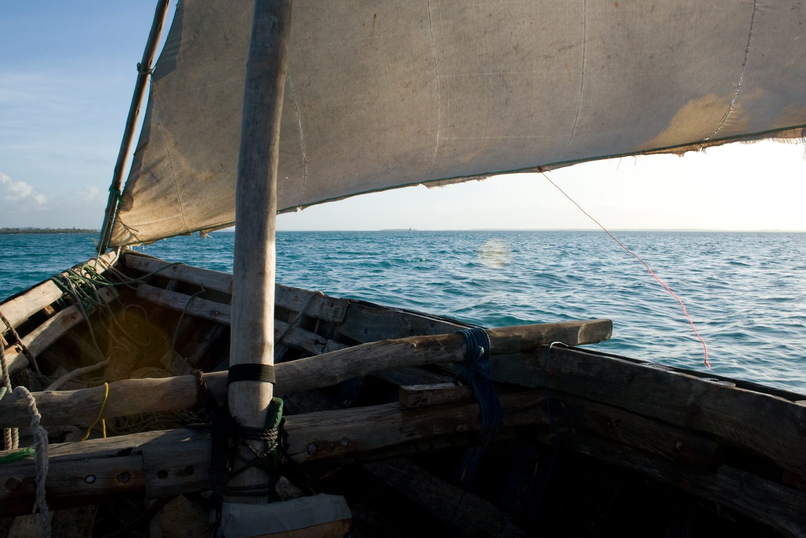 The sail and bow of a traditional dhow under way off Zanzibar