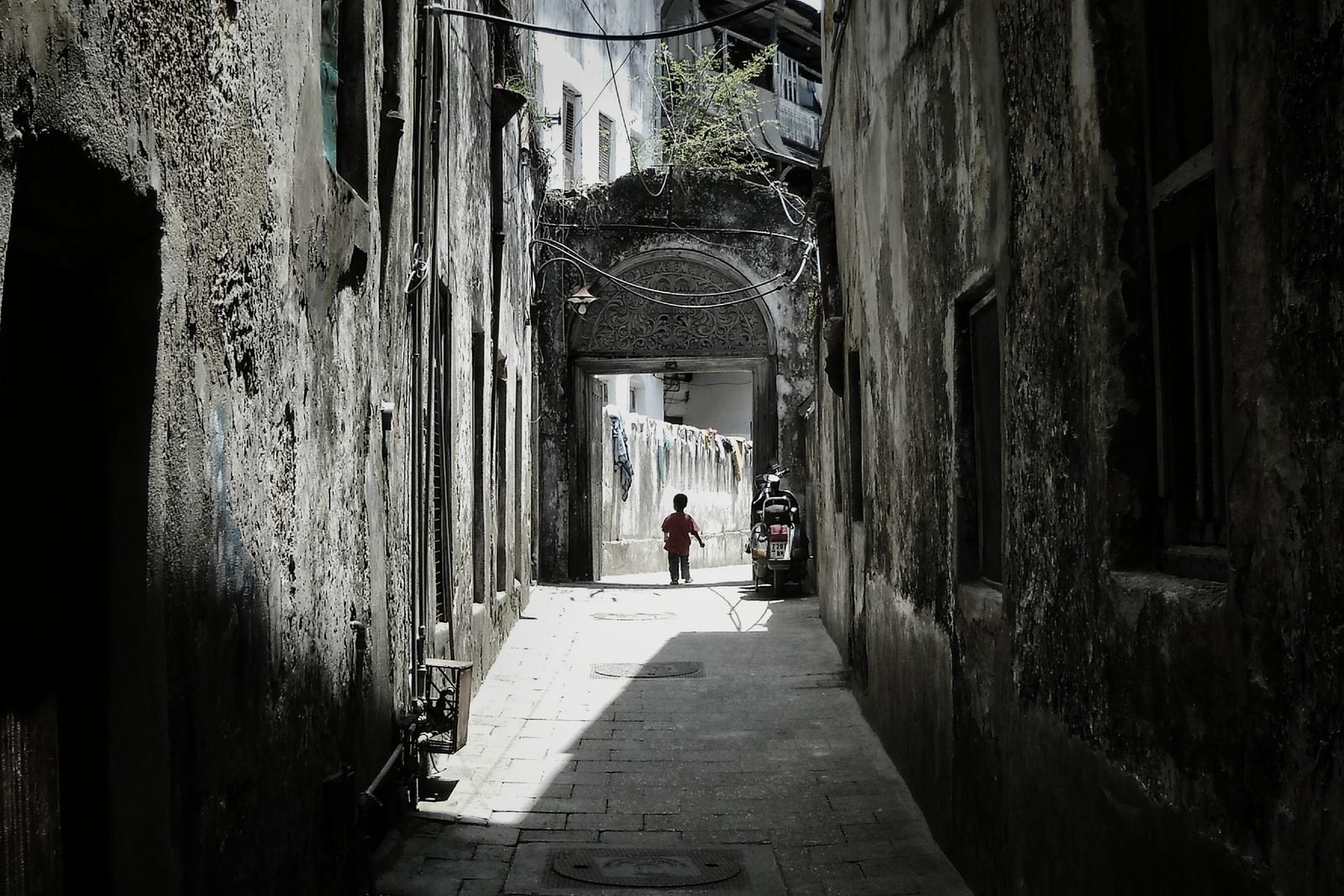 A narrow Stone Town lane between tall coral-rag buildings